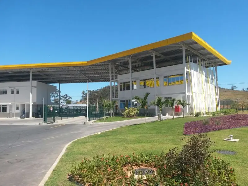 Edifício de apoio do CD Casa e Vídeo, em Queimados/RJ, com cobertura metálica amarela e jardim na entrada.