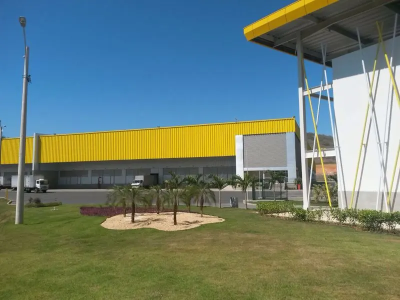 Fachada do galpão do CD Casa e Vídeo, em Queimados/RJ, com fechamento metálico amarelo, docas e área ajardinada.