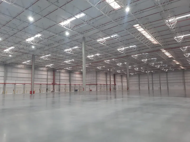 CD CLRG Galeão no Rio de Janeiro/RJ: interior do armazém com pilares de concreto, cobertura metálica treliçada e iluminação zenital