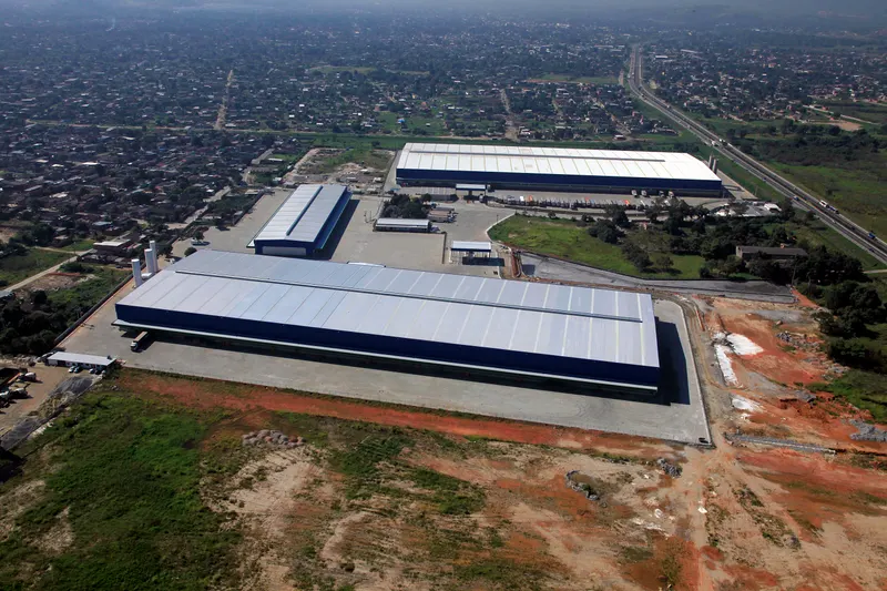 Vista aérea do complexo do CD L'Oréal, em Duque de Caxias/RJ, com os galpões e a área urbana ao redor.