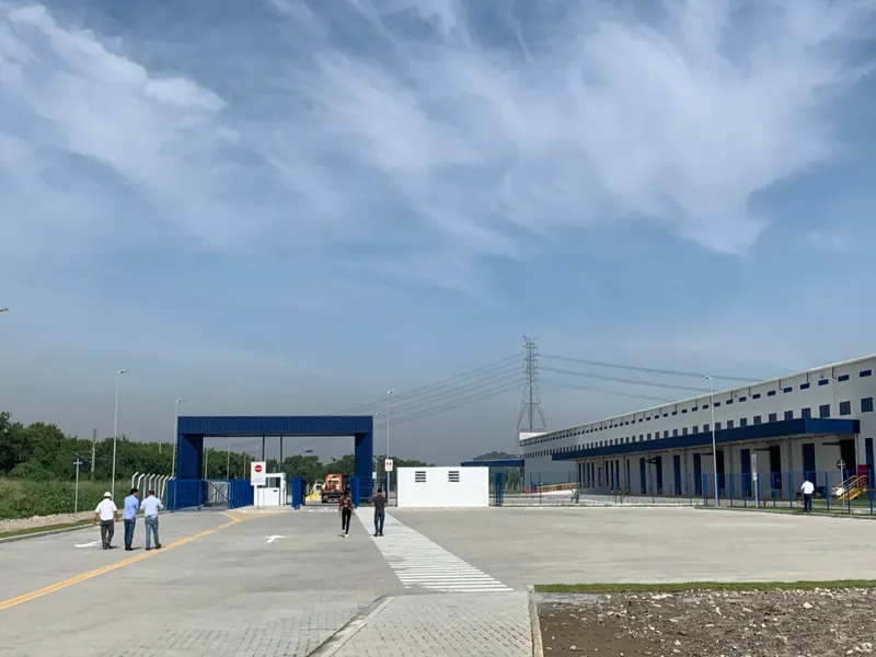 Pátio e portaria do Condomínio Logístico BZLog, em Duque de Caxias/RJ, com o galpão e suas docas à direita.