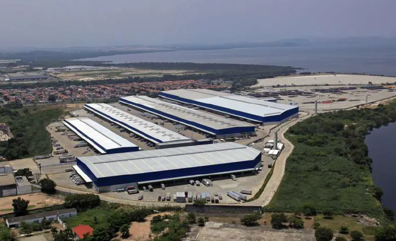 Vista aérea do Terminal de Cargas Cargo Park com galpões, pátio de carretas e a baía ao fundo